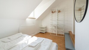 Un dormitorio con techo inclinado, cama, armario y espejo.