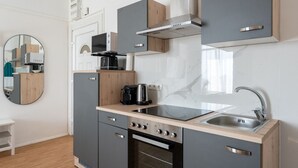 Una cocina moderna con armarios grises, un lavamanos de acero inoxidable, horno empotrado y cafetera.