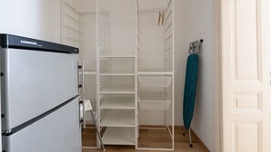 Una habitación con un refrigerador Liebherr, un estante blanco y una toalla color aguamarina colgada de un perchero.