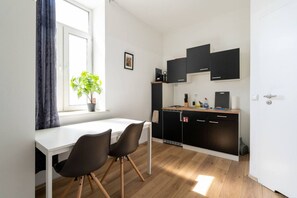 A compact kitchen with a white countertop, black cabinets, and a dining area with two chairs. - FarawayHomes Studio Vienna #1 (Vienna)