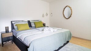 Quarto com cama, mesas de cabeceira, espelho e luminárias fixadas na parede.