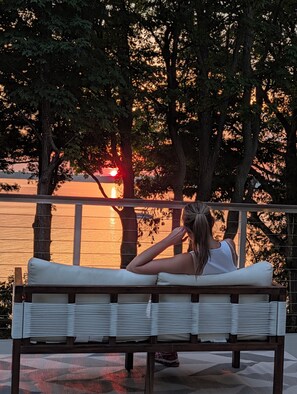 A person sitting on a bench overlooking a body of water with trees in the background.