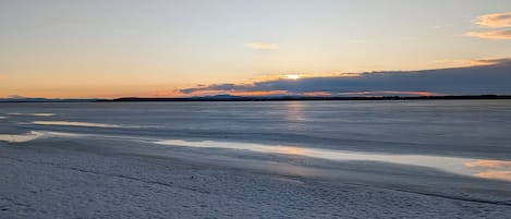 Un lago congelado bajo un cielo despejado y montañas lejanas.