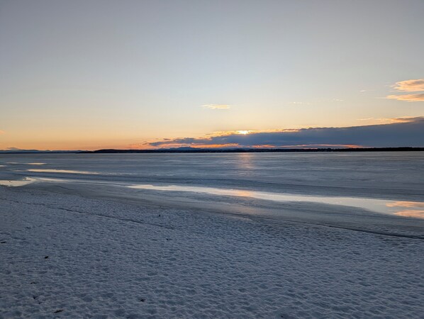A frozen lake with a clear sky and distant mountains.
