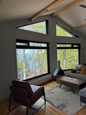 A modern living room with large windows, a sofa, a coffee table, and a fireplace.
