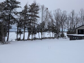 A snow-covered landscape with a house and trees near a body of water. - Sunset View Retreat on Lake Champlain (Alburgh)