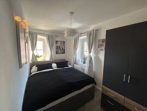 A bedroom with a bed, a wardrobe, and a window with curtains.