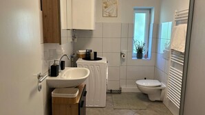 Pieni kylpyhuone, jossa on pesuallas, wc ja pieni ikkuna.