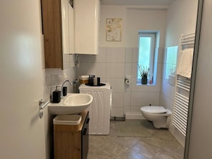 A compact bathroom with a sink, toilet, and a small window.