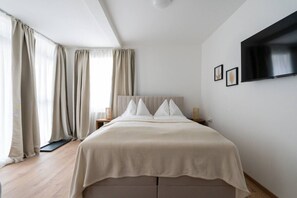 A bedroom with a bed, curtains, a TV, and a nightstand. - FarawayHomes Studio Fohnsdorf #A1 (Fohnsdorf)