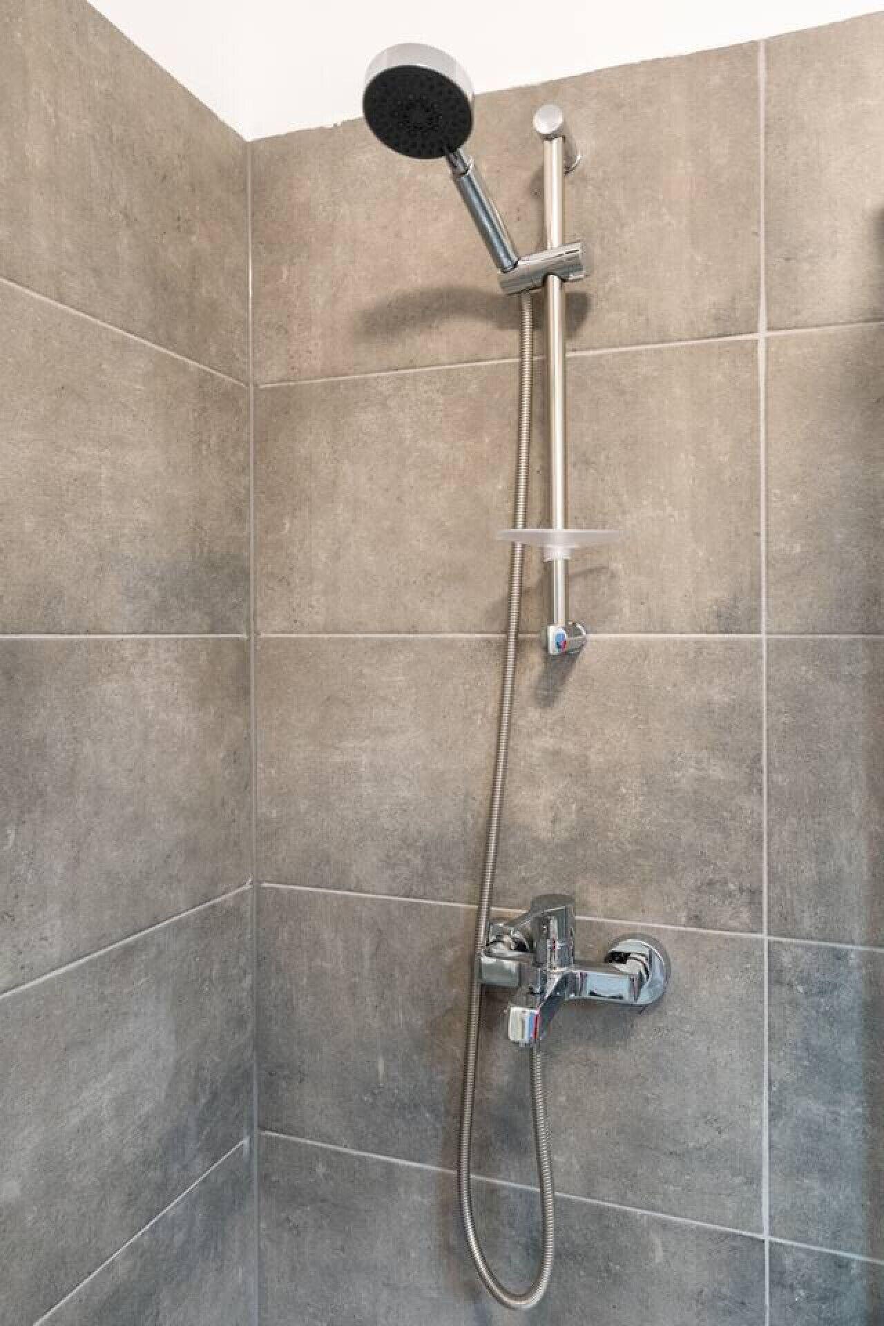 Ducha con cabezal de ducha de mano, grifo empotrado en la pared y manguera flexible.