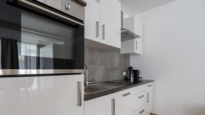 Una cocina moderna con armarios blancos, un horno negro y una cafetera sobre la encimera.