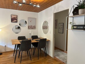 Un comedor con mesa de madera, sillas negras y una lámpara colgante.