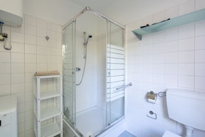 A bathroom with a glass-enclosed shower, a white sink, and a shelf with towels. - FarawayHomes Studio Klosterneuburg #2 (Klosterneuburg)