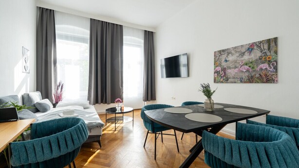 Un soggiorno moderno con un divano, un tavolo da pranzo con sedie, una TV a parete e un quadro.