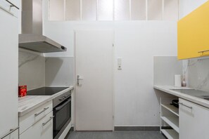 Une cuisine de taille réduite, équipée d’une cuisinière, d’un four et d’une porte blanche.