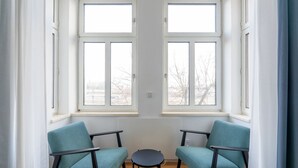 A room with two windows, two chairs, and a small round table.