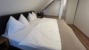 A bedroom with a bed, pillows, a nightstand, and a wooden floor. - FarawayHomes Studio Bruck #5 (Bruck an der Mur)