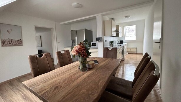 A modern kitchen with white cabinets, a wooden dining table, and brown chairs. - FarawayHomes Studio Bruck #5 (Bruck an der Mur)