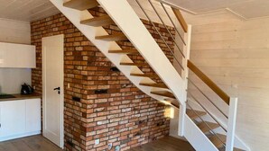 Un escalier avec un mur en briques, des marches en bois et une porte blanche.