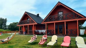Un bâtiment rouge doté d’un balcon et d’une pelouse aménagée avec des chaises longues.