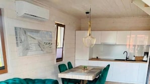 Une cuisine moderne avec des meubles blancs, une table à manger avec des chaises et un luminaire suspendu.