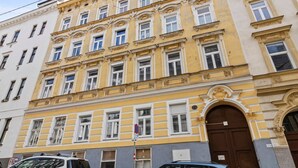En bygning med flere etager, en gul facade, store vinduer og en markant indgang.