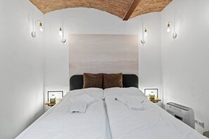 Ein Schlafzimmer mit einem Bett, zwei Nachttischen, einem Heizgerät und Wandleuchten.
