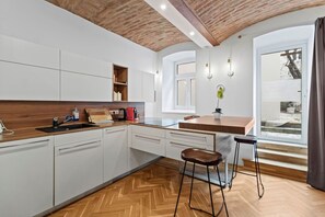 Eine moderne Küche mit weißen Schränken, einer Holzarbeitsplatte, einem eingebauten Backofen und einem großen Fenster.