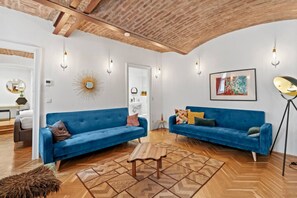 Ein modernes Wohnzimmer mit zwei blauen Sofas, einem Holztisch und einem gemusterten Teppich.