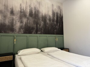 Una stanza con un letto, due comodini e un murale raffigurante una foresta.