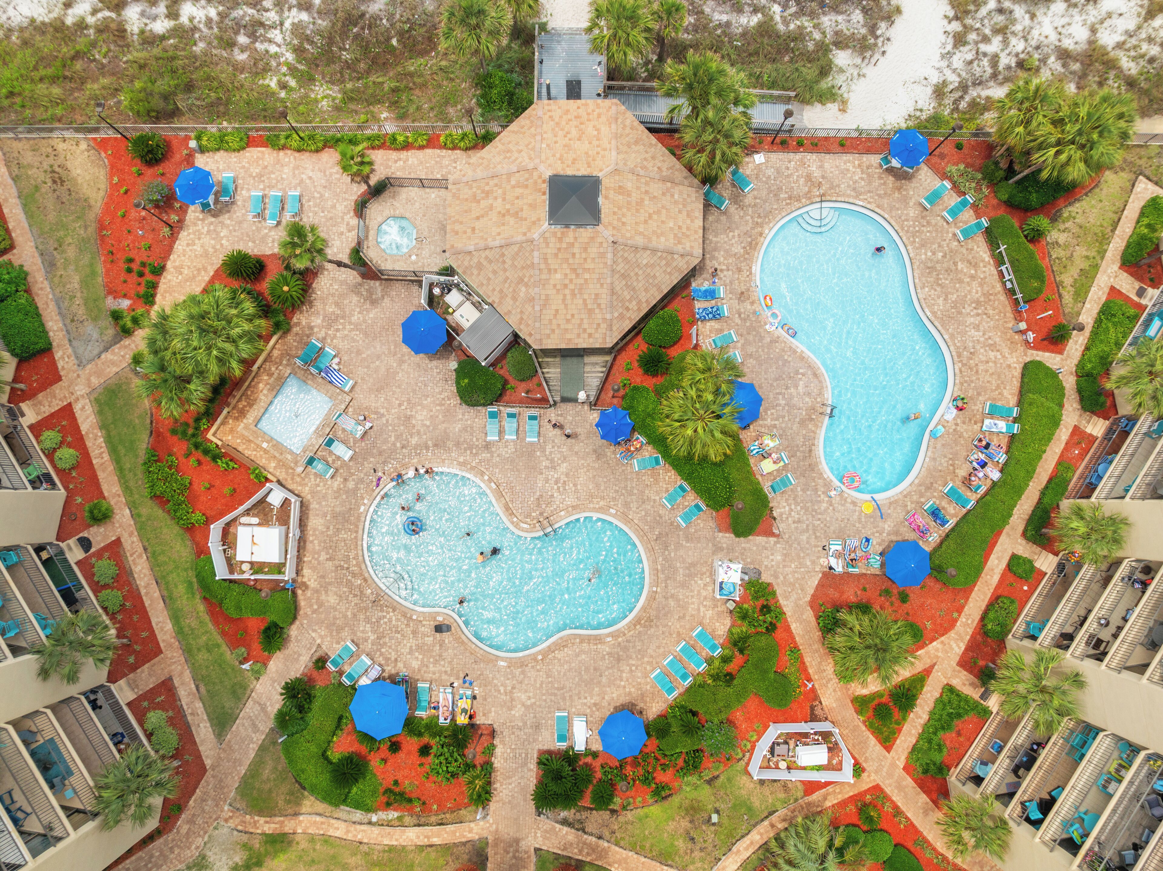 A rooftop pool area with multiple swimming pools, sun loungers, and umbrellas.
