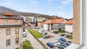 A residential area with a parking lot, buildings with red roofs, and a view of a hilly landscape. - FarawayHomes Studio Leoben #P81 (Donawitz)