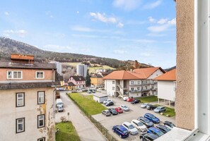 Ein Wohngebiet mit Parkplatz, Gebäuden mit roten Dächern und Blick auf eine hügelige Landschaft.