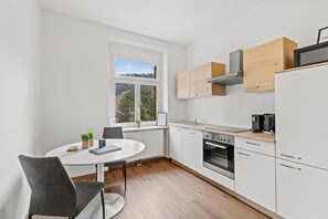 A modern kitchen with white cabinets, a built-in oven, and a microwave. - FarawayHomes Studio Leoben #K7 (Donawitz)