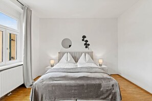 A bedroom with a bed, two bedside tables with lamps, a window with curtains, and a wall decoration. - FarawayHomes Studio Leoben #K7 (Donawitz)