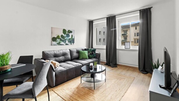 A modern living room with a grey sofa, a round coffee table, and a dining area with a table and chairs. - FarawayHomes Studio Leoben #A5 (Leitendorf)
