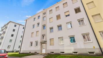 Ein mehrstöckiges Wohngebäude mit flacher Fassade, zahlreichen Fenstern und einem gut sichtbaren Eingang.