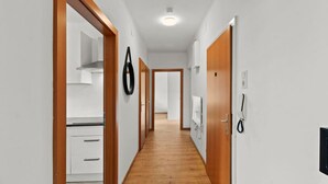 A hallway with wooden flooring, white walls, and a kitchen area visible on the left. - FarawayHomes Studio Leoben #A5 (Leitendorf)