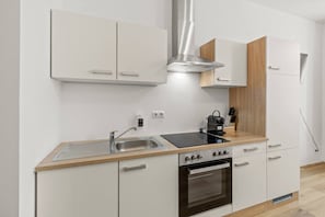 A modern kitchen with white cabinetry, a stainless steel range hood, a built-in oven, and a black induction cooktop. - FarawayHomes Studio Vienna #2 (Vienna)
