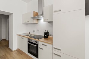 A modern kitchen with white cabinetry, a wooden countertop, a built-in oven, and a stainless steel range hood. - FarawayHomes Studio Vienna #2 (Vienna)