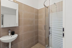 A bathroom with a sink, mirror, and shower. - FarawayHomes Studio Vienna #2 (Vienna)