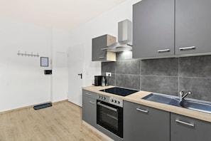 Una cocina moderna con armarios grises, estufa negra y encimera de madera.