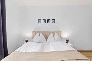 Una habitación de hotel moderna con cama, mesitas de noche y cuadros en la pared.