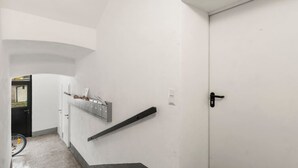Ein Flur mit einer weißen Tür, einem Briefschlitz und einem Fahrrad, das an der Wand lehnt.