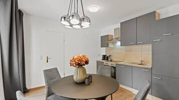 A modern kitchen with grey cabinets, a round dining table, and a vase with flowers.