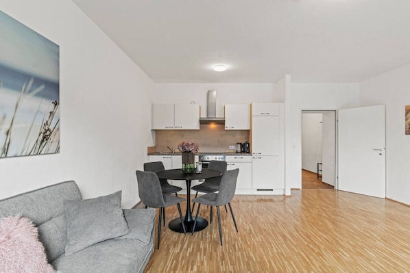 A modern apartment with a dining area, kitchen, and living room.