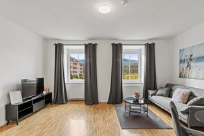 Un soggiorno moderno con una TV a schermo piatto, un divano, un tavolino da caffè e un quadro appeso al muro.