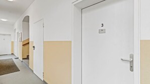 Um corredor com portas, carpete e escada.