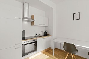 Eine kompakte Küche mit Herd, Backofen und Spüle, einem kleinen Tisch und einem Stuhl.